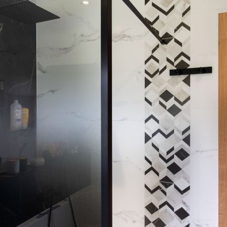 Rénovation salle de bain moderne avec douche, baignoire et carrelage effet marbre noir