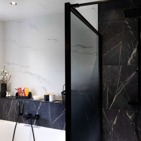 Rénovation salle de bain moderne avec douche, baignoire et carrelage effet marbre noir