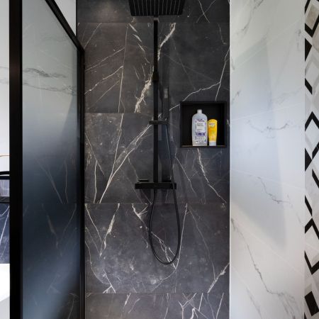 Rénovation salle de bain moderne avec douche, baignoire et carrelage effet marbre noir