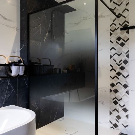 Rénovation salle de bain moderne avec douche, baignoire et carrelage effet marbre noir
