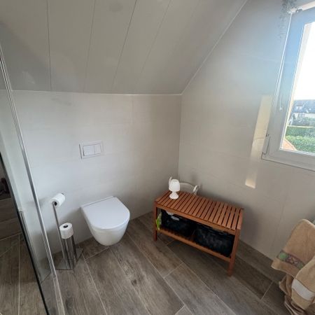 Aménagement d’un espace douche sous pente avec carrelage effet bois