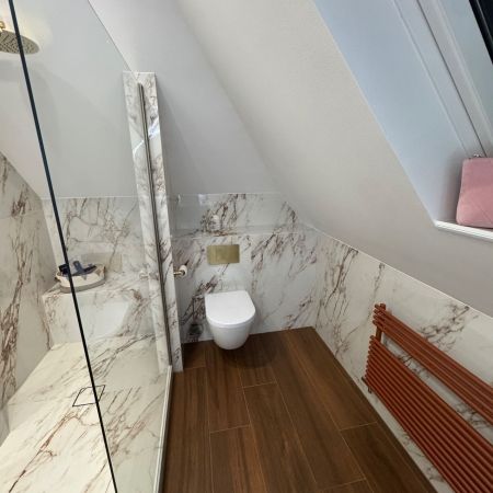 Une salle de bains sous combles élégante entre effet marbre et imitation bois