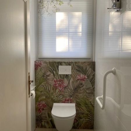 Rénovation de toilette PMR avec WC suspendu et carrelage décoratif tropical Rénovation de toilette PMR avec WC suspendu et carrelage décoratif tropical