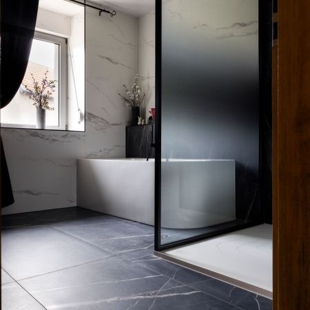 Rénovation salle de bain moderne avec douche, baignoire et carrelage effet marbre noir